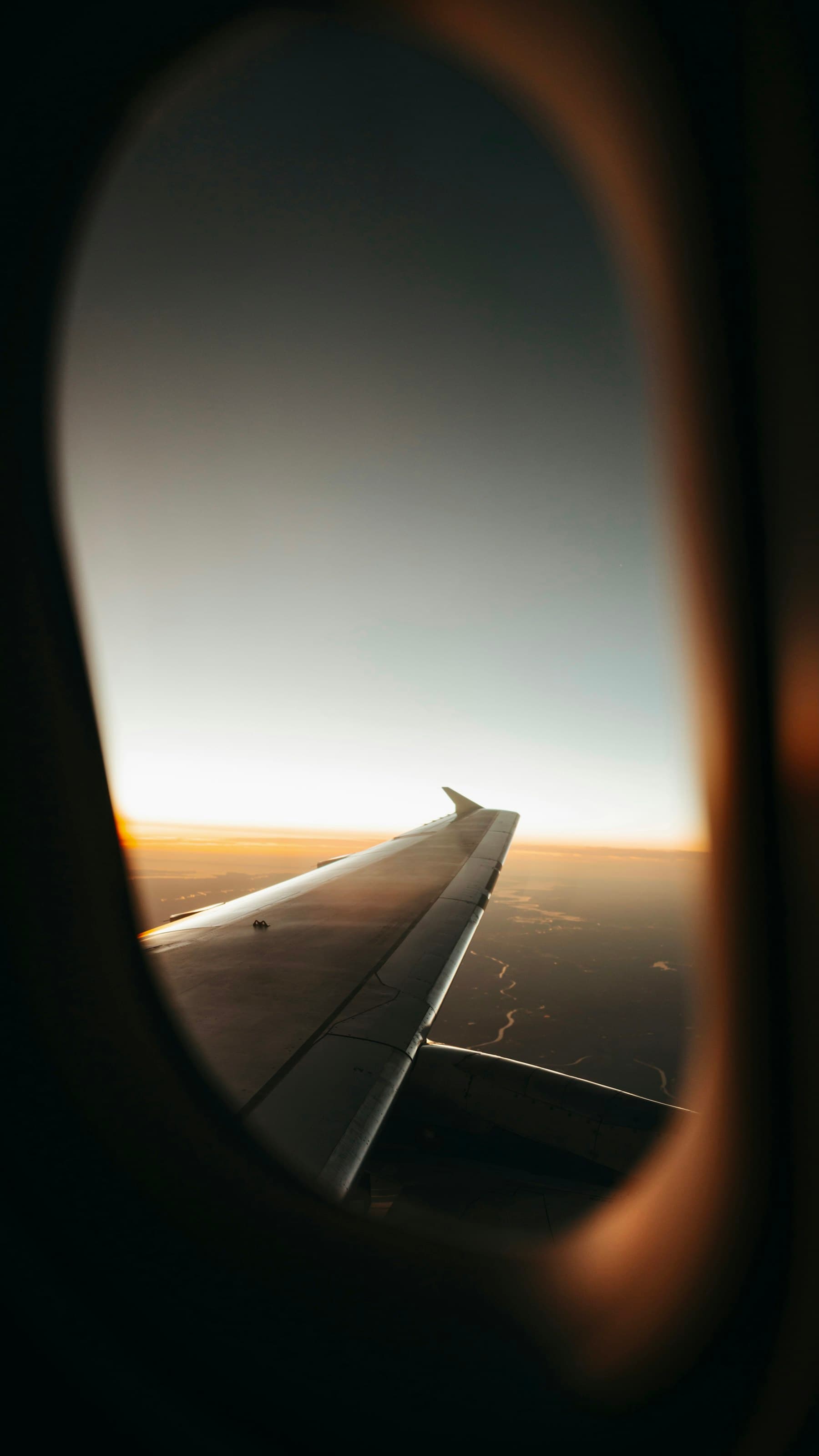 Asa de avião sobre as nuvens ao entardecer